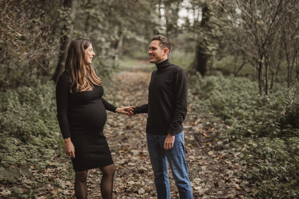 Mann und Frau stehen in der Natur mit Babybauch