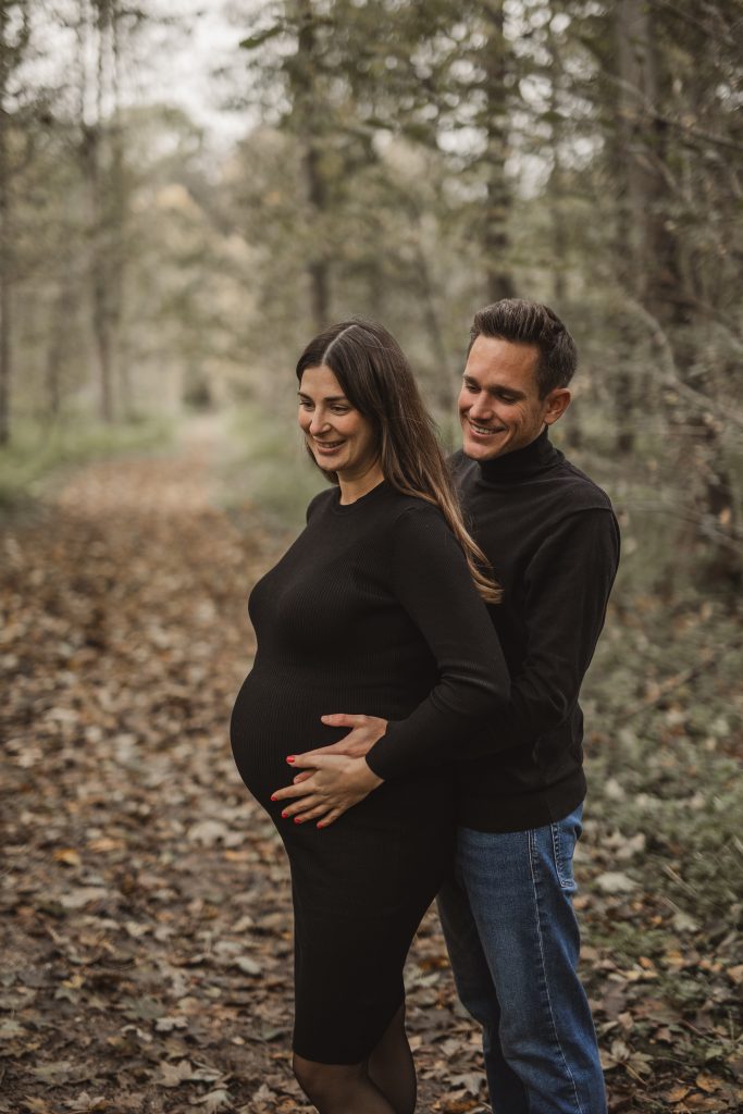 Mann und Frau stehen in der Natur mit Babybauch