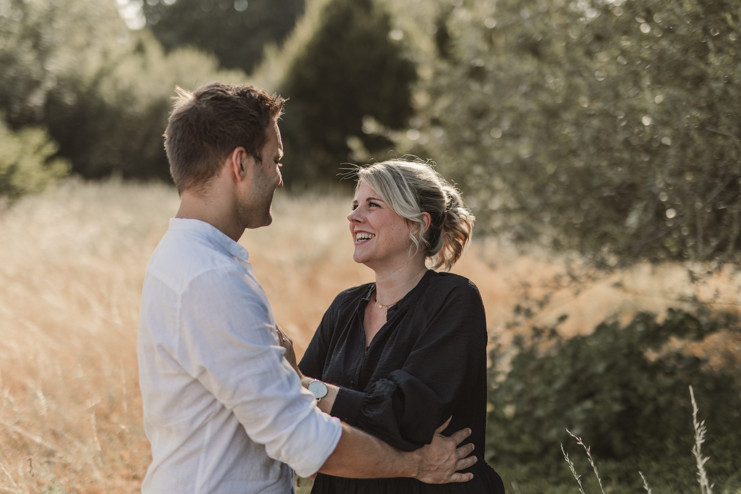 Paar steht lachend in der Natur und schaut sich an