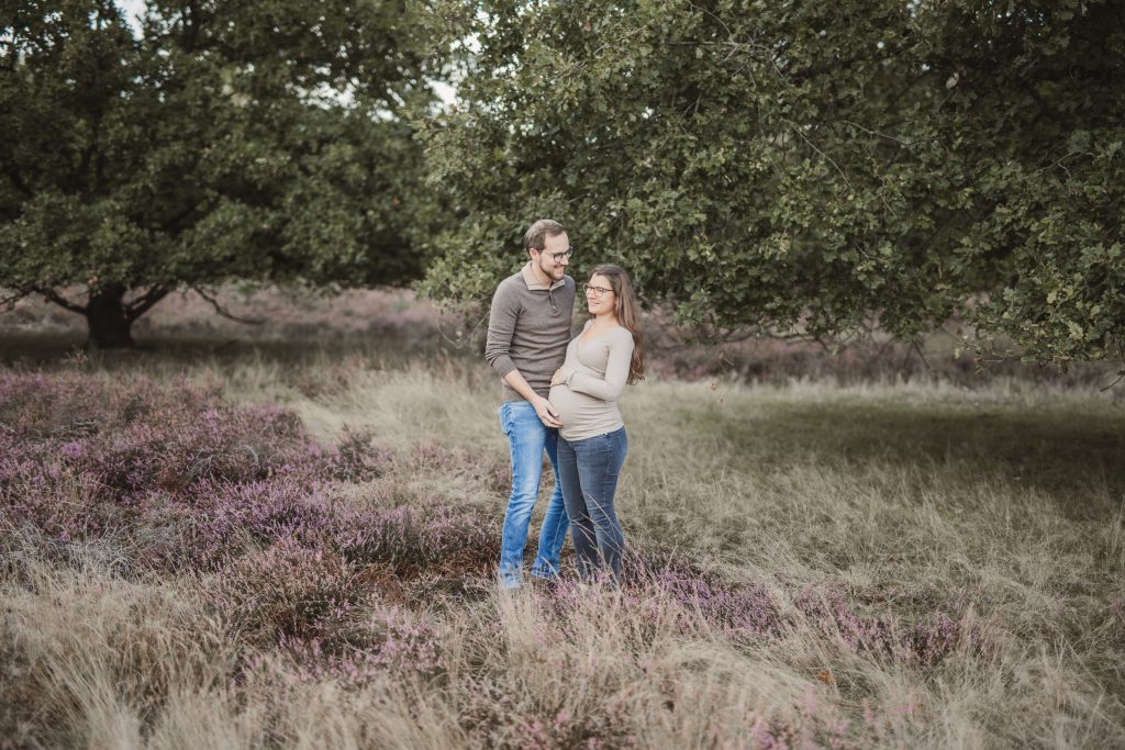 Mann und Frau stehen in der Natur mit Babybauch