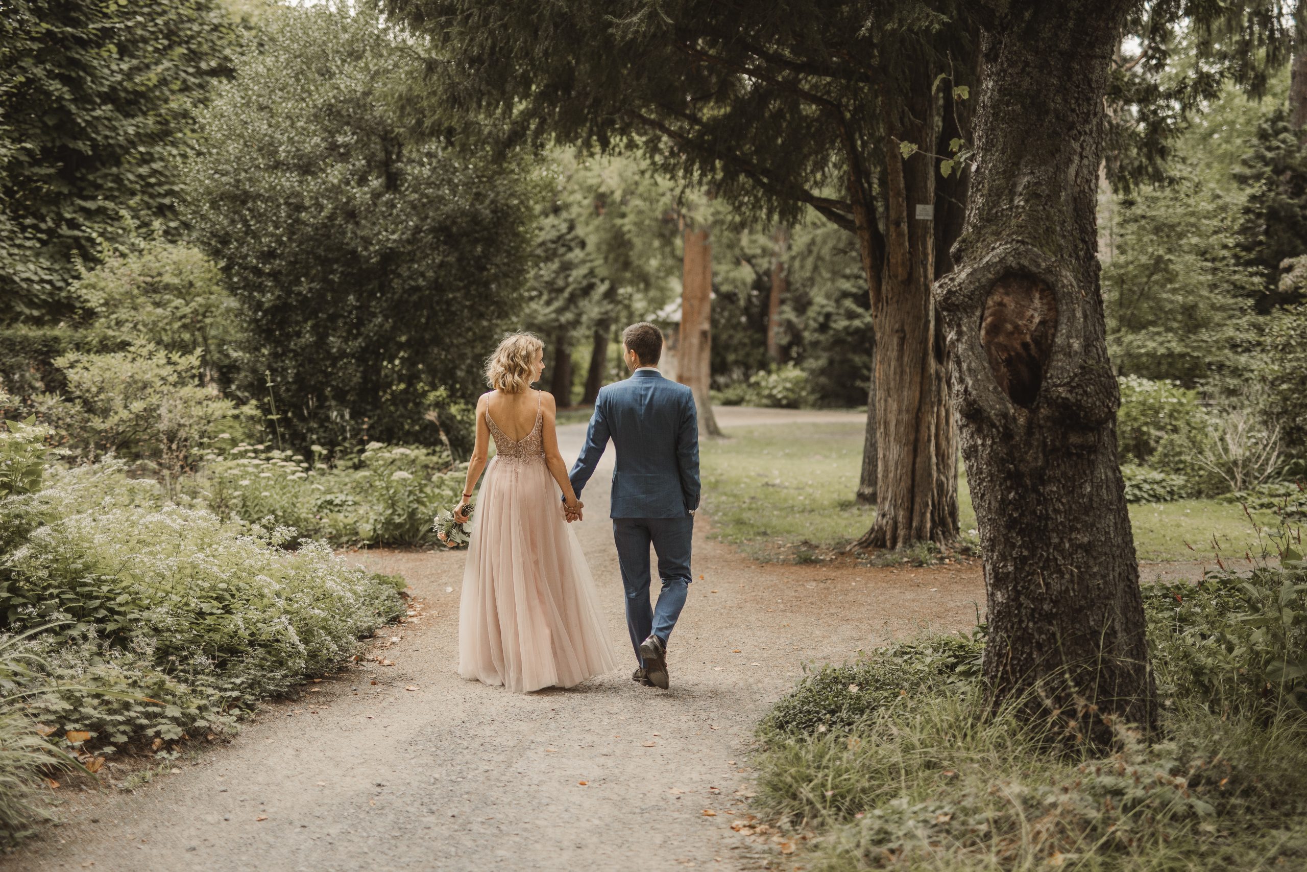Hochzeitspaar läuft händchenhaltend durch den Park