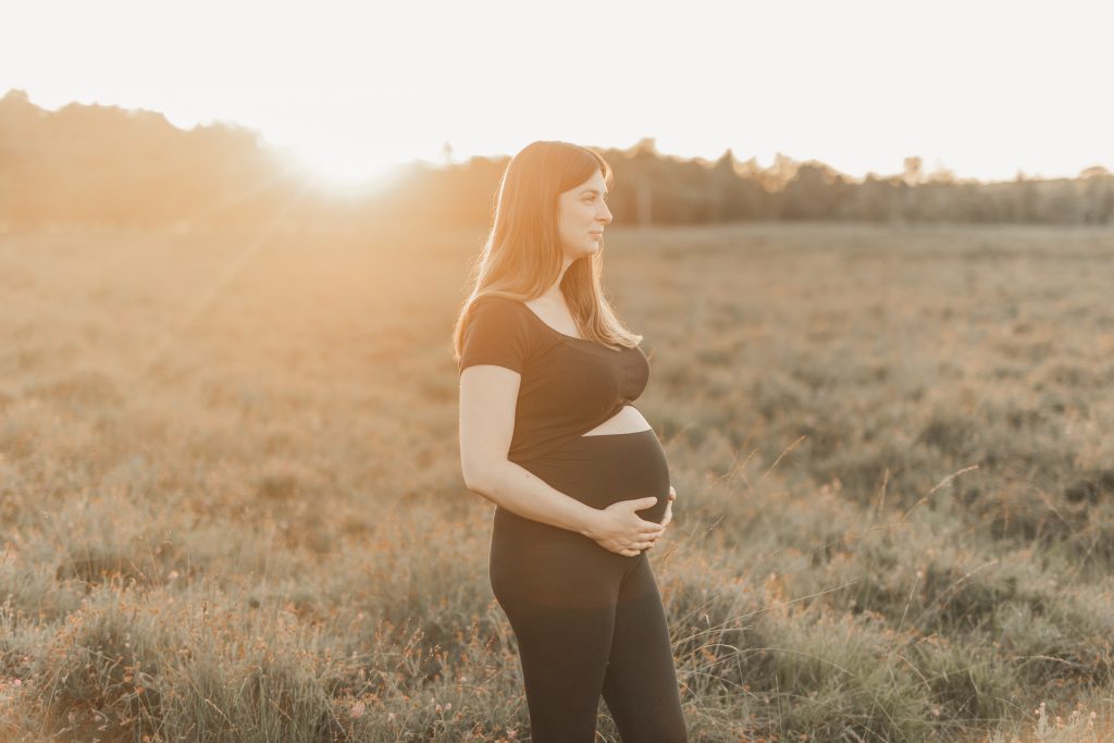 Schwangere Frau steht vor dem Sonnenuntergang